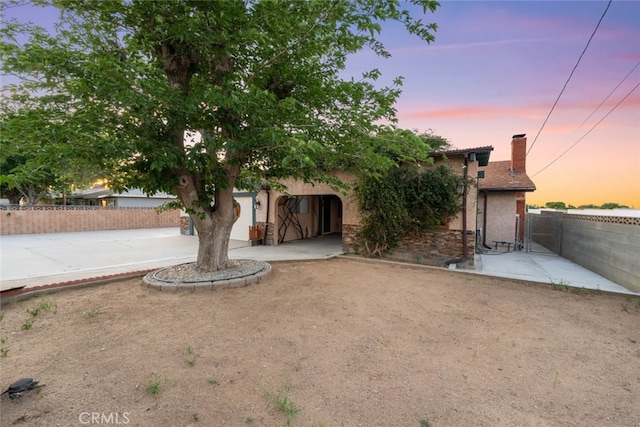 5111 W W Ave M2, Lancaster, CA 93536 - view of property hidden behind natural elements featuring a chimney, fence, stucco siding, and driveway