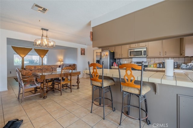 5111 W W Ave M2, Lancaster, CA 93536 - kitchen featuring appliances with stainless steel finishes, tile countertops, cream cabinetry, and backsplash