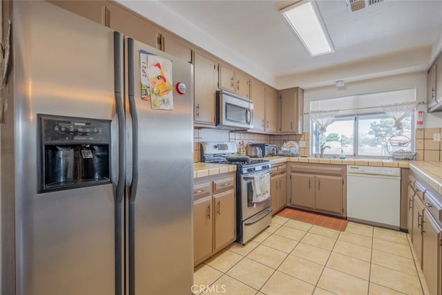 5111 W W Ave M2, Lancaster, CA 93536 - kitchen featuring appliances with stainless steel finishes, decorative backsplash, light tile patterned flooring, tile counters, and a sink