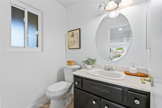 half bath with toilet, vanity, and baseboards