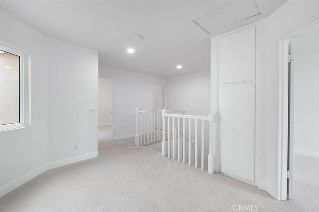 empty room featuring recessed lighting, carpet flooring, baseboards, and attic access