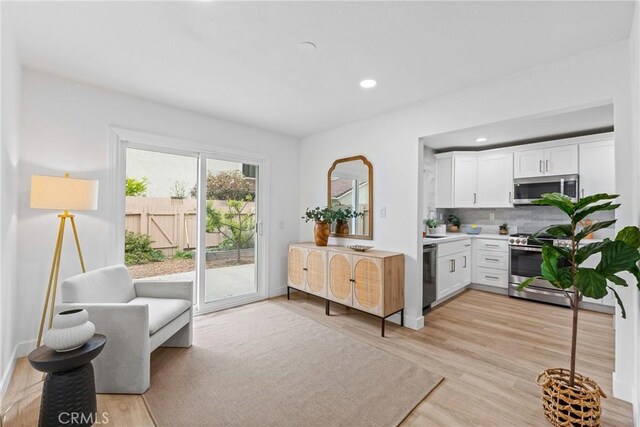 kitchen with decorative backsplash, light wood-style floors, stainless steel appliances, light countertops, and white cabinetry