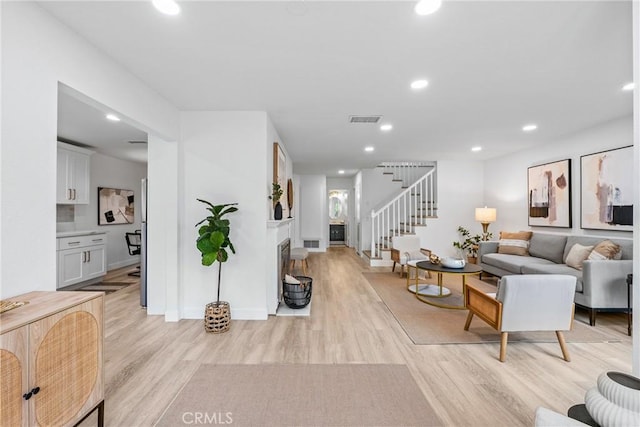 living area featuring light wood finished floors, visible vents, recessed lighting, and stairway