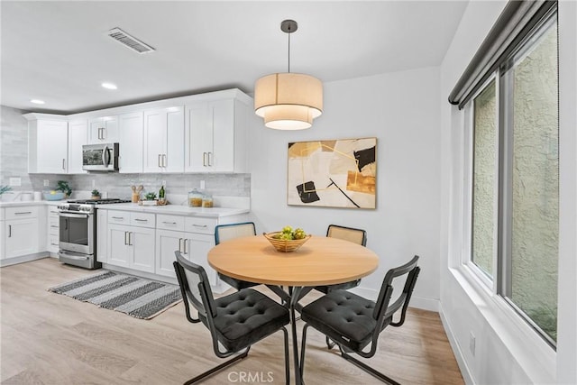 kitchen featuring stainless steel appliances, visible vents, decorative backsplash, and light wood-style floors