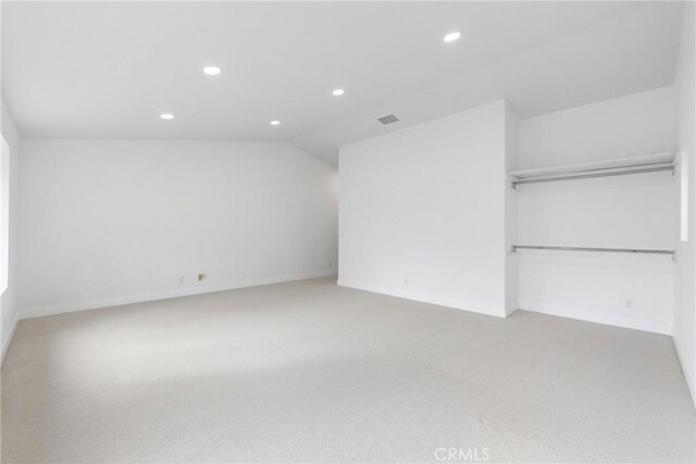 unfurnished bedroom with vaulted ceiling, visible vents, recessed lighting, light colored carpet, and a closet
