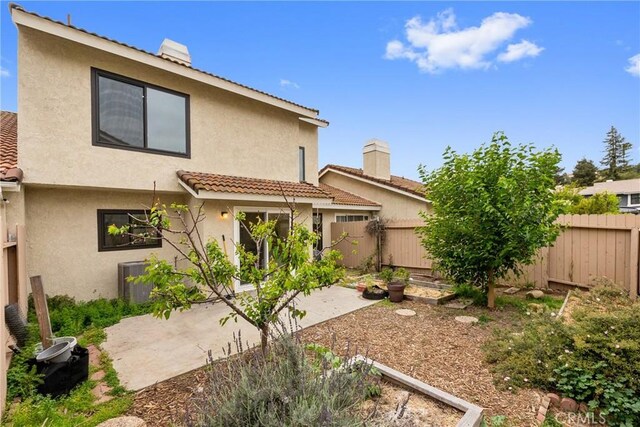 rear view of house with a tiled roof, a patio, a fenced backyard, and stucco siding