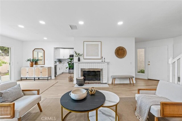 living area with a fireplace, visible vents, light wood finished floors, and recessed lighting