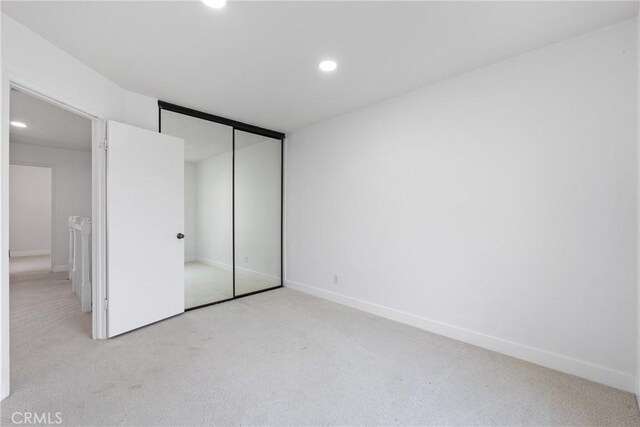 unfurnished bedroom featuring recessed lighting, a closet, baseboards, and light carpet