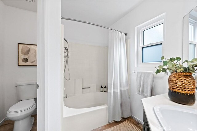 full bathroom with toilet, a healthy amount of sunlight, wood finished floors, and shower / bathtub combination with curtain