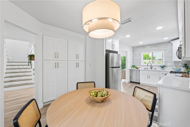dining room featuring stairway, light wood finished floors, visible vents, and recessed lighting