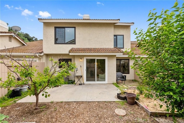 rear view of property featuring a patio area, a tiled roof, stucco siding, and fence