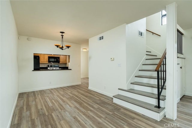 527 E Elmwood Ave Unit E, Burbank, CA 91501 - unfurnished living room with a chandelier, light wood-style floors, stairs, visible vents, and baseboards