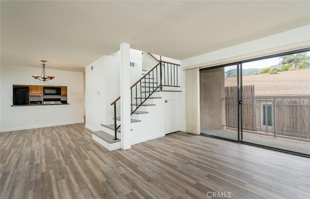 527 E Elmwood Ave Unit E, Burbank, CA 91501 - unfurnished living room with a chandelier, stairway, and wood finished floors