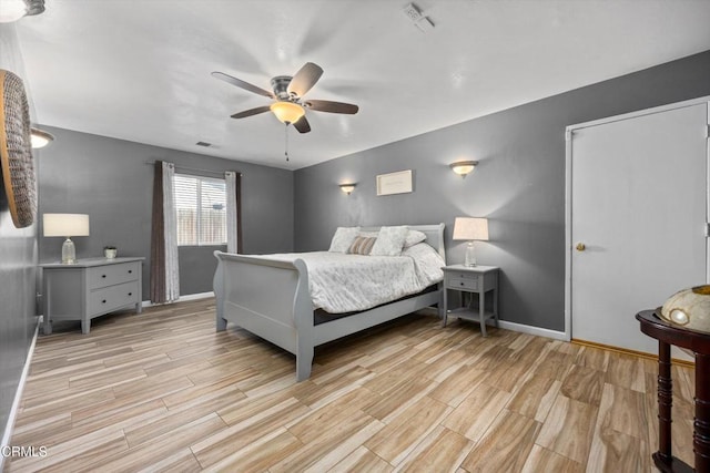 bedroom with baseboards, a ceiling fan, visible vents, and light wood-type flooring