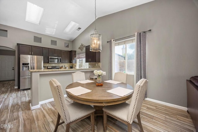 dining room with light wood finished floors, an inviting chandelier, vaulted ceiling, visible vents, and baseboards