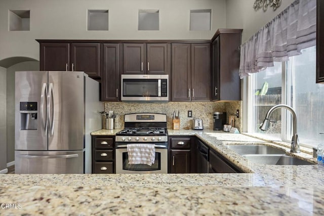 kitchen featuring tasteful backsplash, appliances with stainless steel finishes, dark brown cabinetry, and a sink