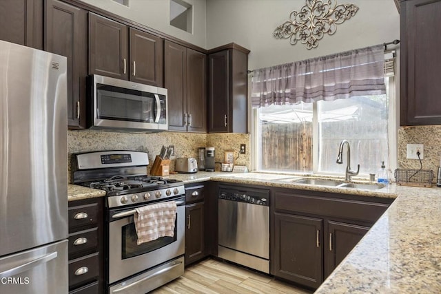 kitchen with backsplash, dark brown cabinetry, stainless steel appliances, and a sink
