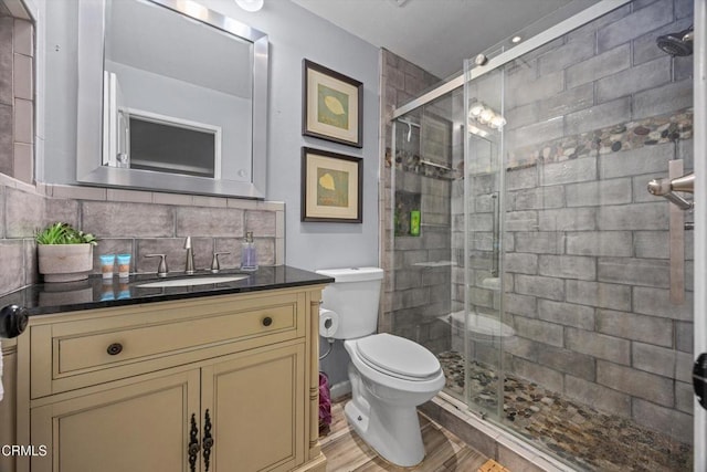 bathroom with decorative backsplash, toilet, vanity, and a stall shower