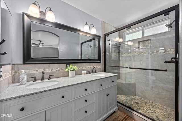 bathroom with a ceiling fan, a sink, double vanity, and a stall shower