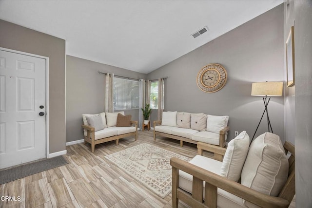 living area with baseboards, vaulted ceiling, visible vents, and light wood-style floors