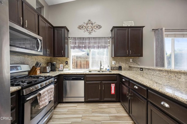 kitchen featuring dark brown cabinets, tasteful backsplash, appliances with stainless steel finishes, and a sink