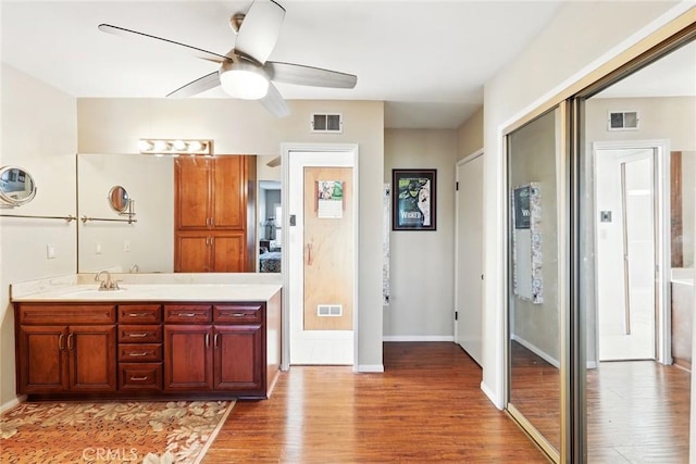 bathroom with visible vents, wood finished floors, vanity, and ceiling fan