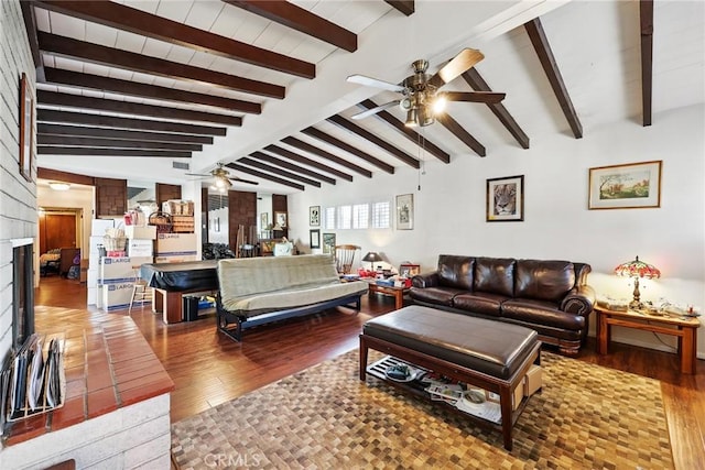 living area with a ceiling fan, wood finished floors, vaulted ceiling with beams, and a fireplace