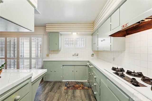 kitchen featuring white gas stovetop, a sink, green cabinets, and tile countertops