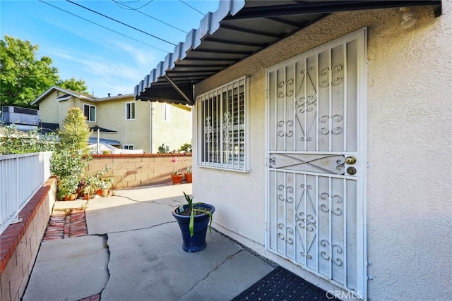 property entrance featuring stucco siding and fence