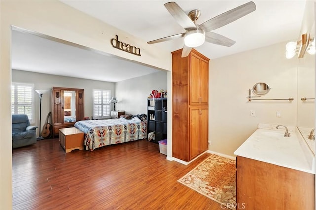 bedroom with ceiling fan, multiple windows, wood finished floors, and a sink