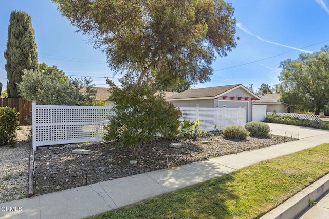 view of front of home with concrete driveway, a garage, and fence private yard