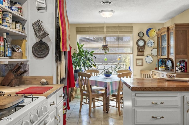 dining space featuring visible vents, a textured ceiling, and light tile patterned floors