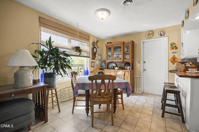 dining room with light tile patterned flooring, a textured ceiling, and visible vents