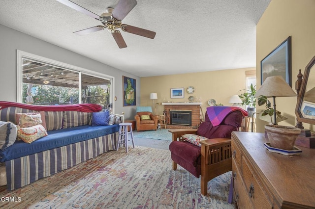 living area featuring ceiling fan, a wealth of natural light, a textured ceiling, and a fireplace