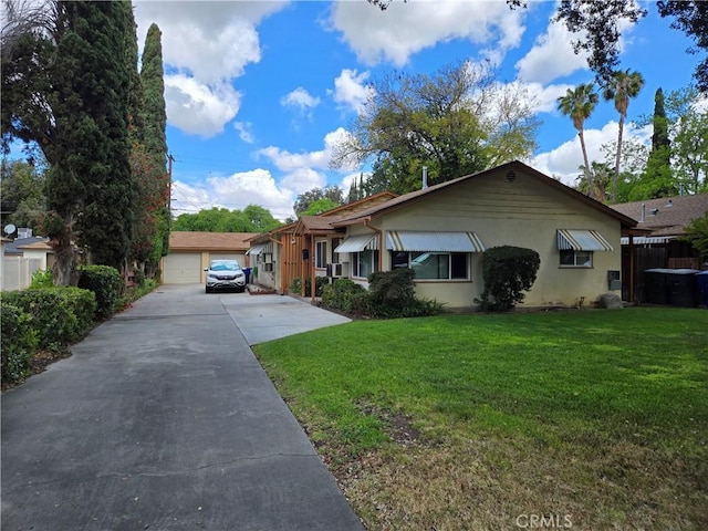 view of front facade featuring a detached garage, an outdoor structure, a front yard, and stucco siding