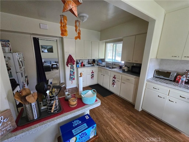 kitchen with dark wood-type flooring, a sink, black microwave, and light countertops