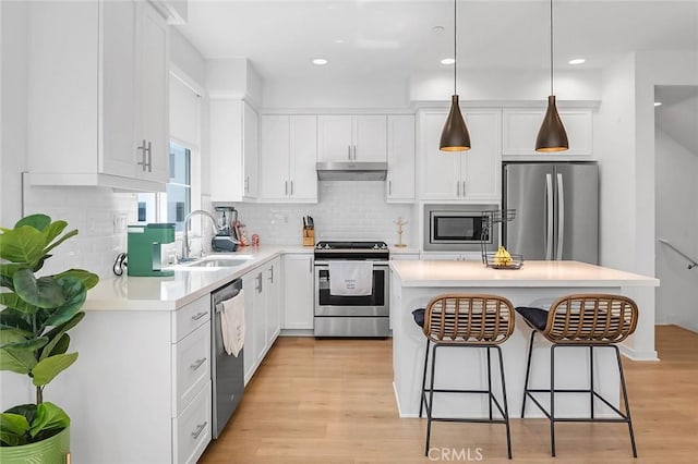 208 Novel, Irvine, CA 92618 - kitchen with stainless steel appliances, a kitchen breakfast bar, white cabinetry, light wood finished floors, and light countertops