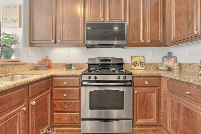 44936 Honey Locust Dr, Temecula, CA 92592 - kitchen with a sink, brown cabinets, appliances with stainless steel finishes, and light stone counters