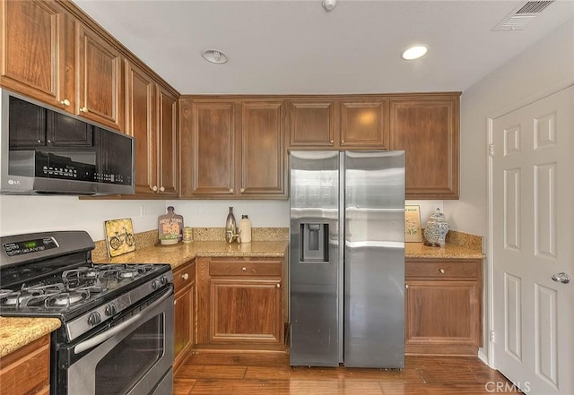 44936 Honey Locust Dr, Temecula, CA 92592 - kitchen with visible vents, stainless steel appliances, dark wood-type flooring, and light stone counters
