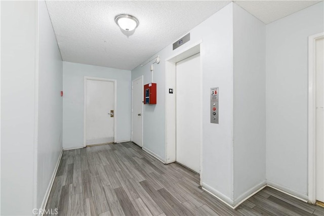 120 S Sierra Madre Blvd Unit 206, Pasadena, CA 91107 - hallway with light wood-type flooring, a textured ceiling, elevator, and baseboards