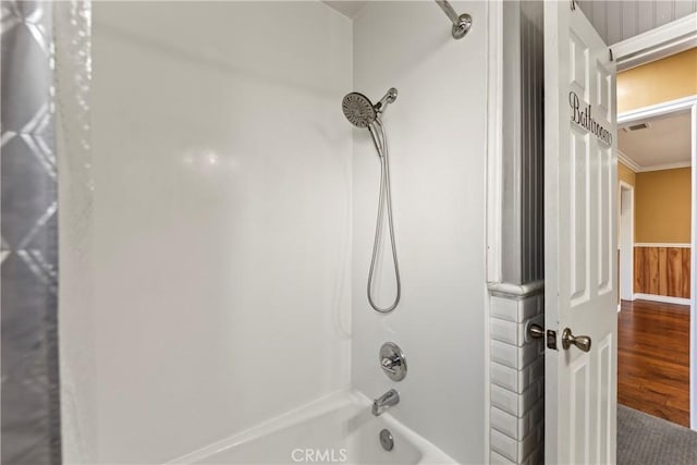 bathroom featuring wood finished floors, tub / shower combination, and ornamental molding