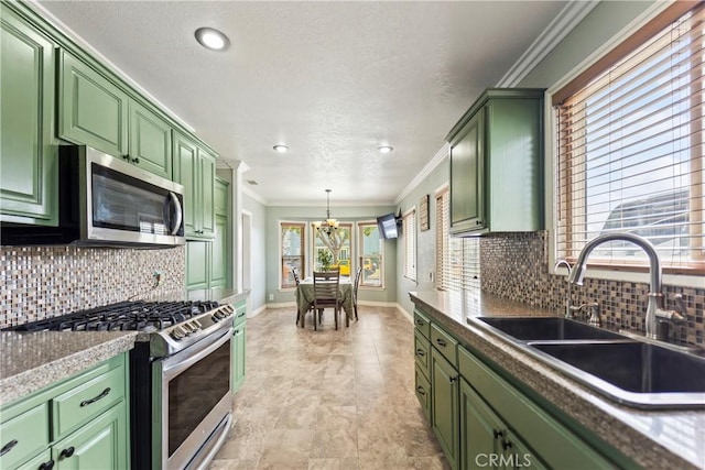 kitchen featuring green cabinetry, stainless steel appliances, a sink, a chandelier, and baseboards