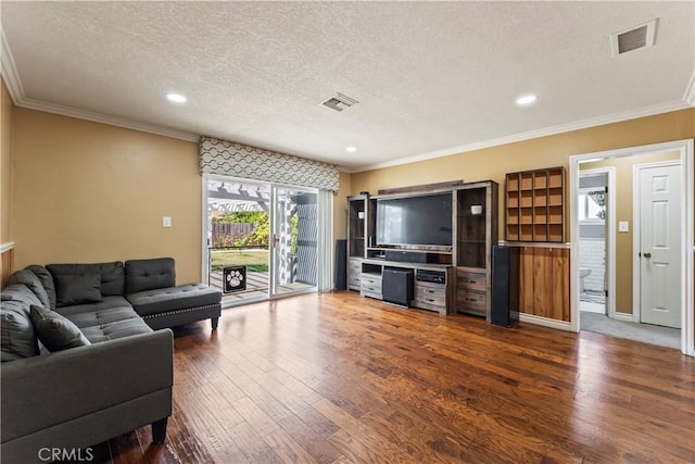 living room featuring a textured ceiling, hardwood / wood-style flooring, crown molding, and recessed lighting
