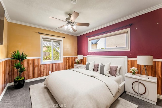 bedroom featuring carpet, wainscoting, multiple windows, wood walls, and ornamental molding