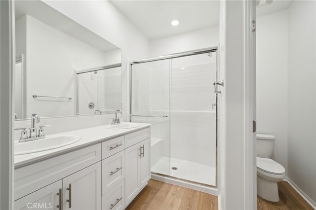 219 Aurora Ln, Pomona, CA 91767 - bathroom with wood finished floors, toilet, double vanity, and a shower stall