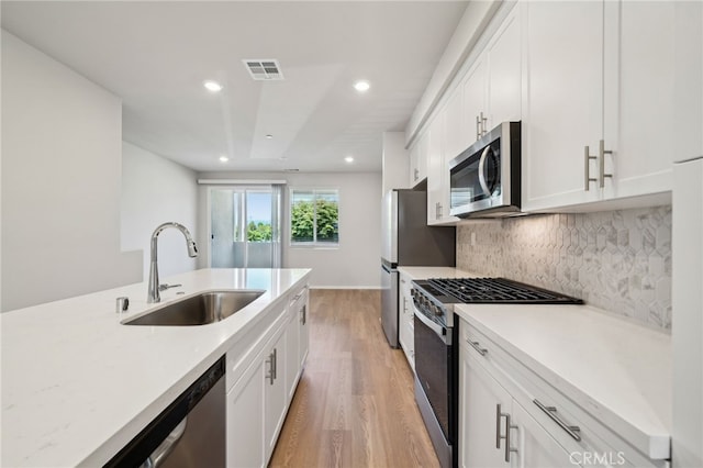 219 Aurora Ln, Pomona, CA 91767 - kitchen with appliances with stainless steel finishes, a sink, light wood-type flooring, light countertops, and white cabinets