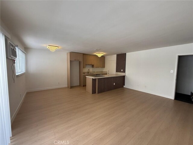 960 Larrabee St Unit 120, West Hollywood, CA 90069 - unfurnished living room featuring a sink, light wood-style floors, baseboards, and a wall unit AC