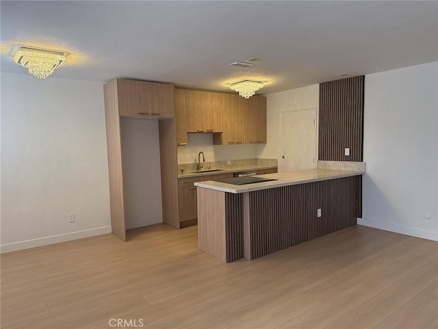 960 Larrabee St Unit 120, West Hollywood, CA 90069 - kitchen featuring light countertops, light wood-style floors, a peninsula, and baseboards