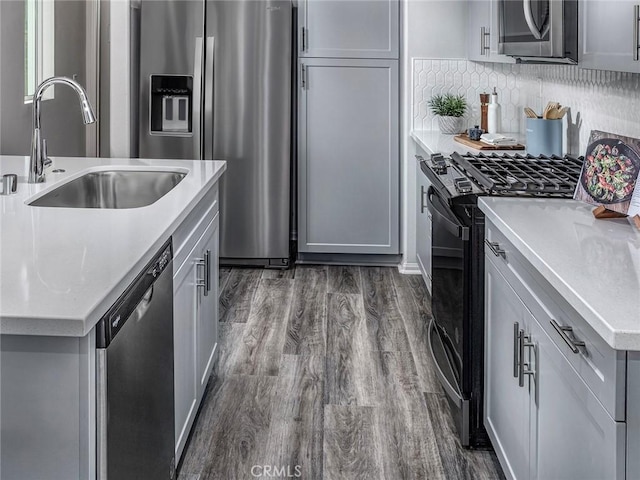 217 Aurora Ln, Pomona, CA 91767 - kitchen featuring a sink, decorative backsplash, appliances with stainless steel finishes, light countertops, and dark wood-style flooring