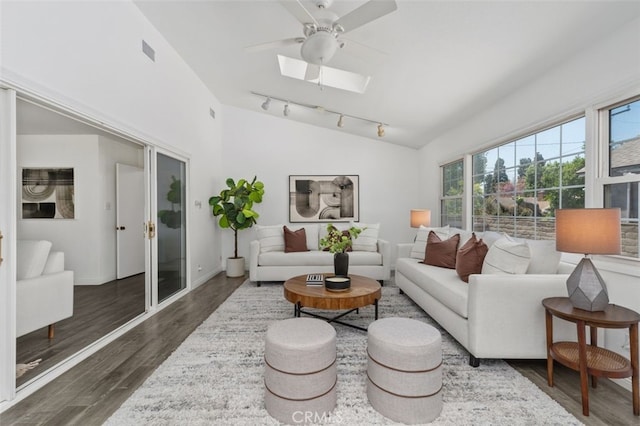 living area featuring lofted ceiling with skylight, visible vents, wood finished floors, and ceiling fan